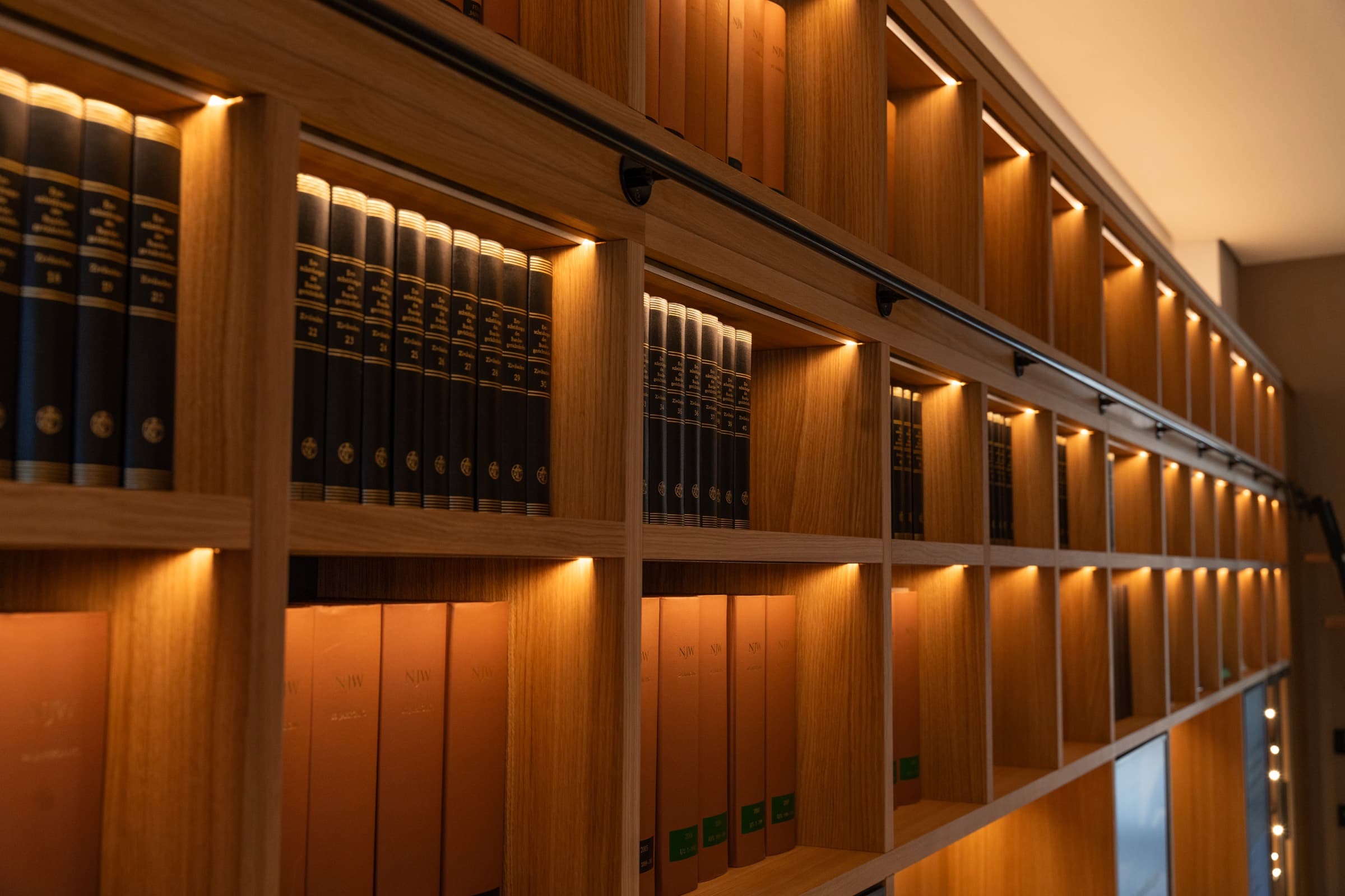Blick in die Bibliothek am Roggenmarkt: beleuchtete Holzregale mit juristischen Bänden